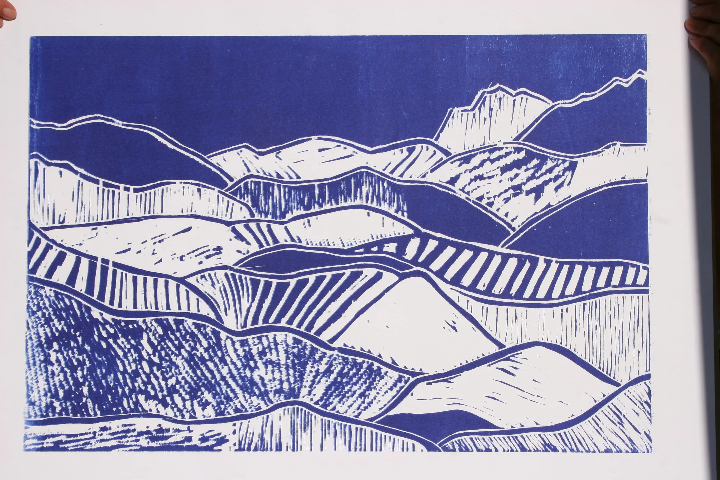 Blau-weißer Holzschnitt einer hügeligen Voralpenlandschaft
